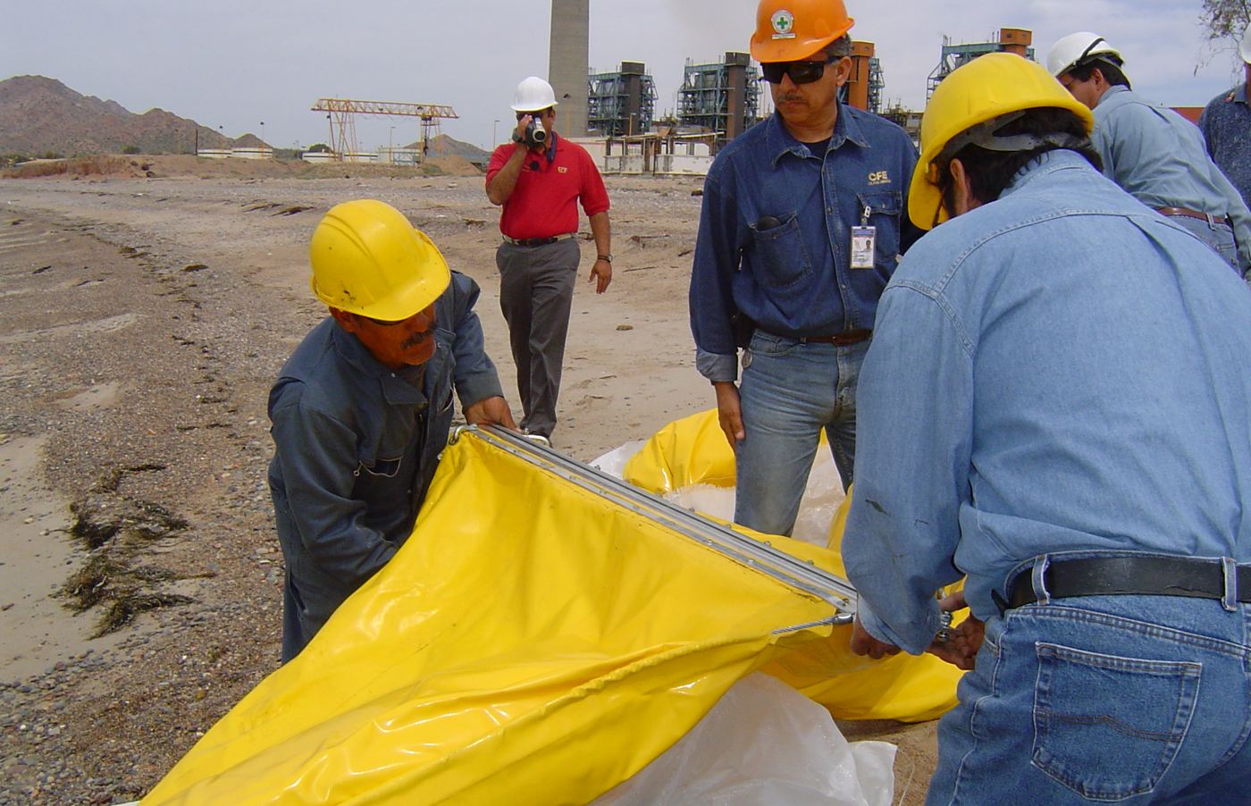 Cuadrilla tendiendo una barrera amarilla en la playa