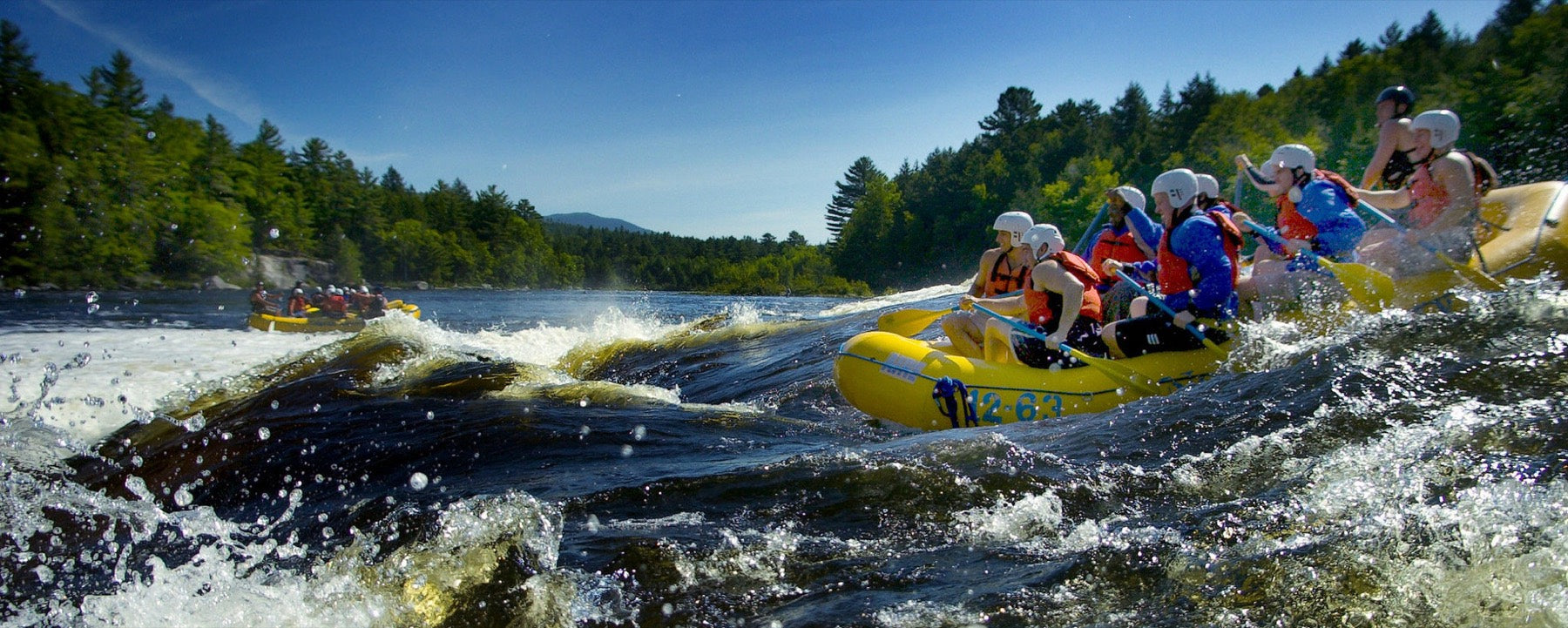 Equipo de rafting con chalecos salvavidas en aguas rápidas